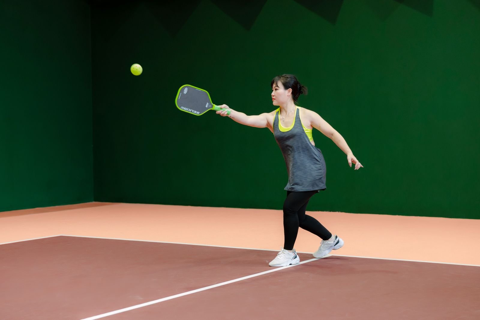 Player driving through a forehand on an indoor court